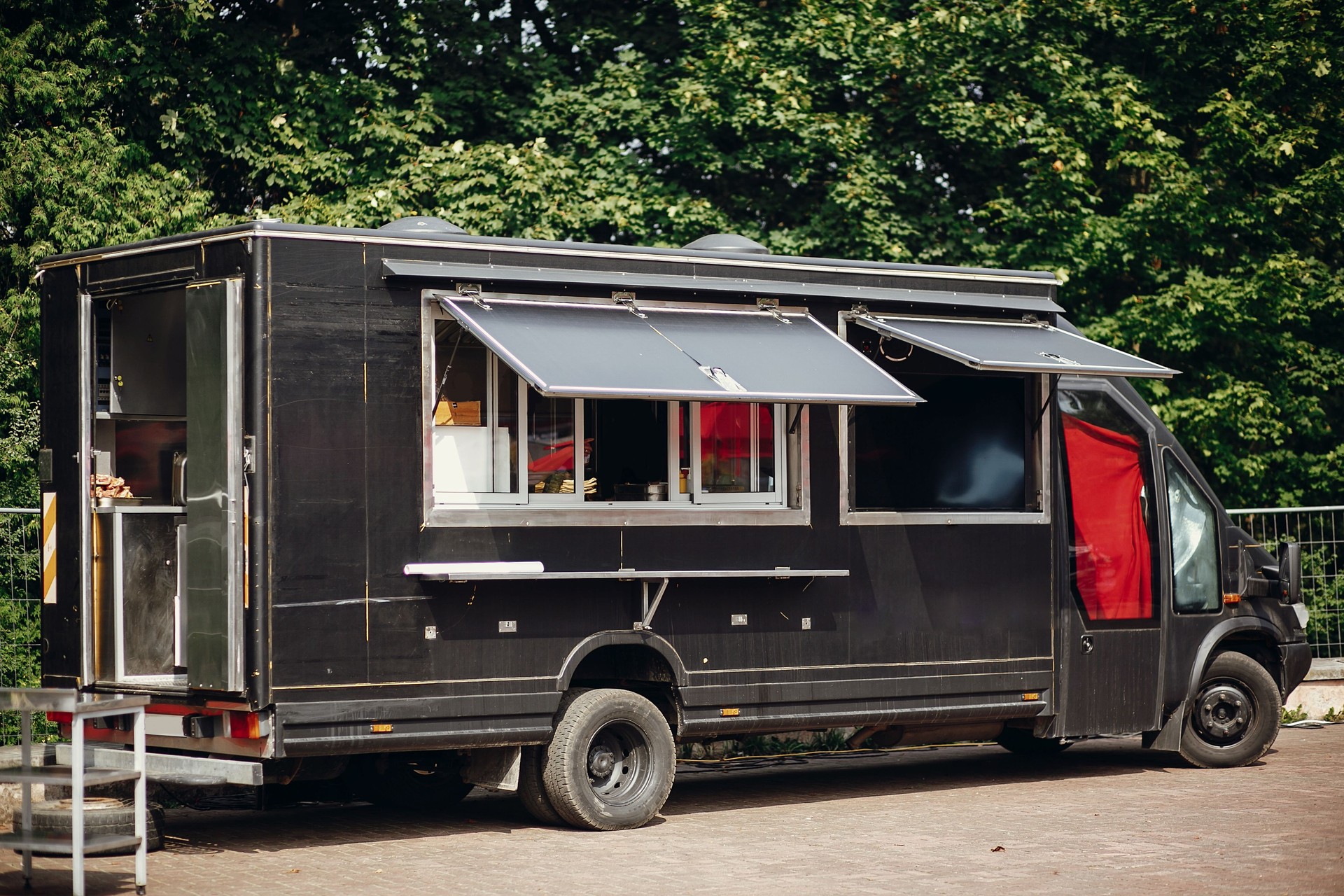 Camion de Food Van. Élégant camion de nourriture mobile noir avec des hamburgers et de la nourriture asiatique au Festival de nourriture de rue. Marché d'été de manger dans la ville. Espace pour le texte, le menu